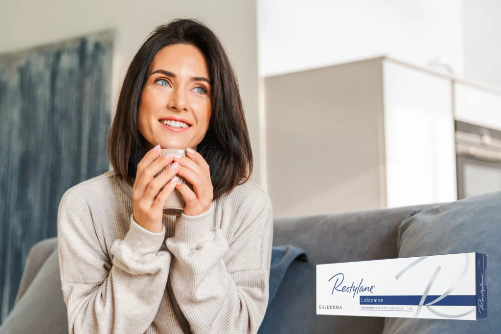 woman sitting on a sofa with a mug looking into the distance happily