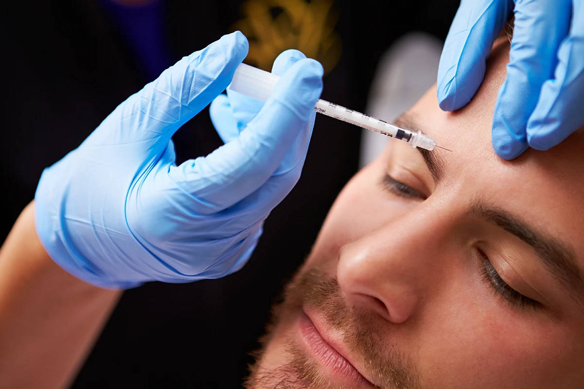 A handsome, middle aged man getting Botox injections in his forehead 