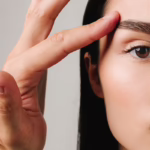 A young woman with smooth skin touches the area around her eye, showing the concept of EMFACE Eye treatment for eye bags and dark circles