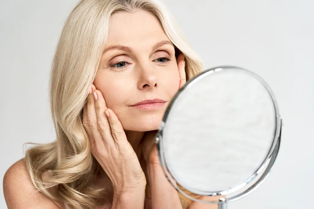 A woman looking in a small round mirror after Botox treatment