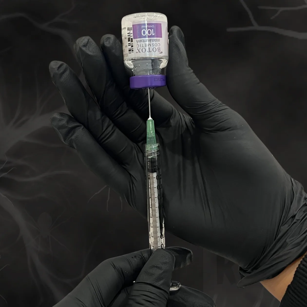 A vial of BOTOX held by hands with black gloves against a black background