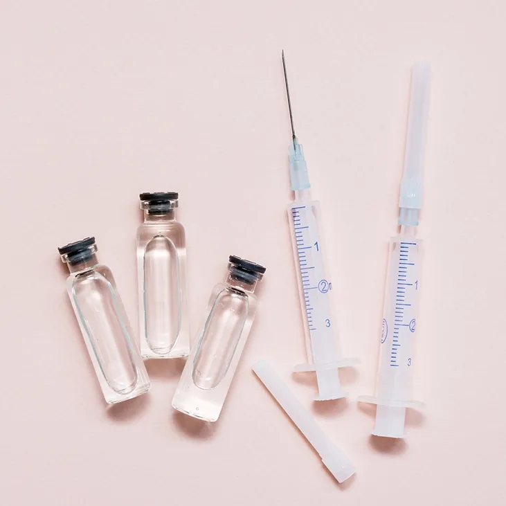 Enzyme injection syringes and vials against a pink background