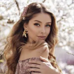 A young woman in a pink dress standing in front of a blossoming tree