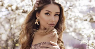 A young woman in a pink dress standing in front of a blossoming tree