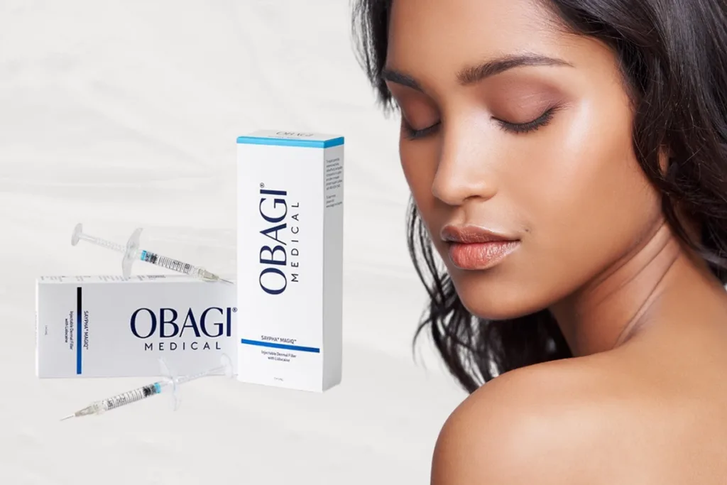 Close up of a beautiful woman's face with perfect skin, no wrinkles, small pores, and no visible signs of aging, with two boxes and syringes of OBAGI MEDICAL MagIQ injectable hyaluronic acid (HA) filler in the background