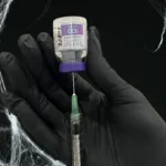 A syringe and a BOTOX vial against a black spiderweb background