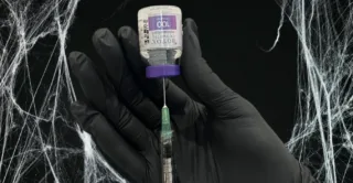 A syringe and a BOTOX vial against a black spiderweb background
